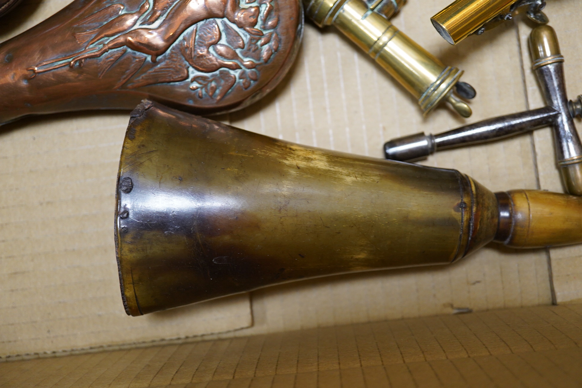 Four assorted copper powder flasks comprising; a three-way flask by Sykes (dented), ‘three horses head’ flask by Hawksley and two others, together with two leather shot flasks, a horn powder flask and a percussion nipple